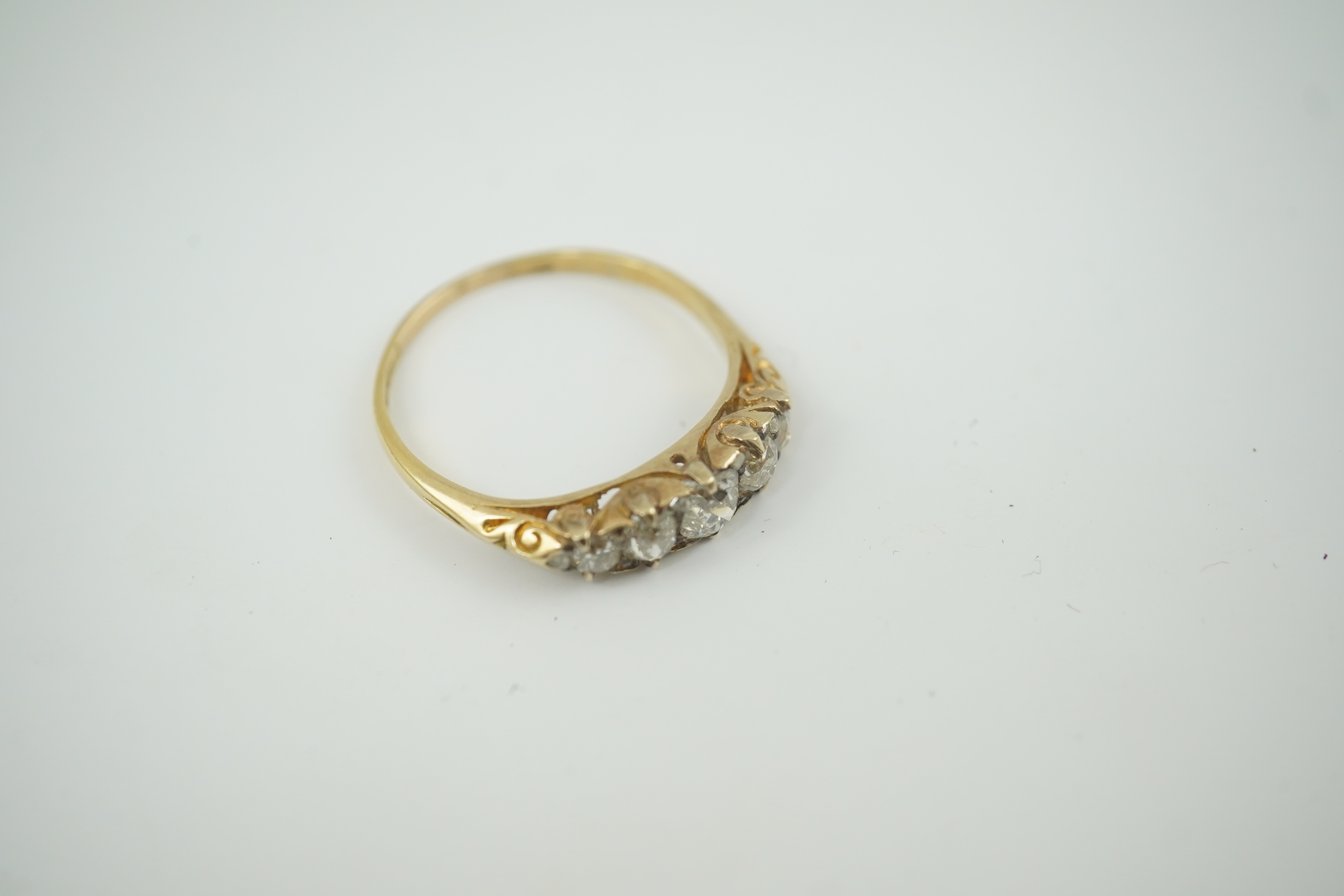 An early 20th century gold and graduated five stone old cut diamond set half hoop ring